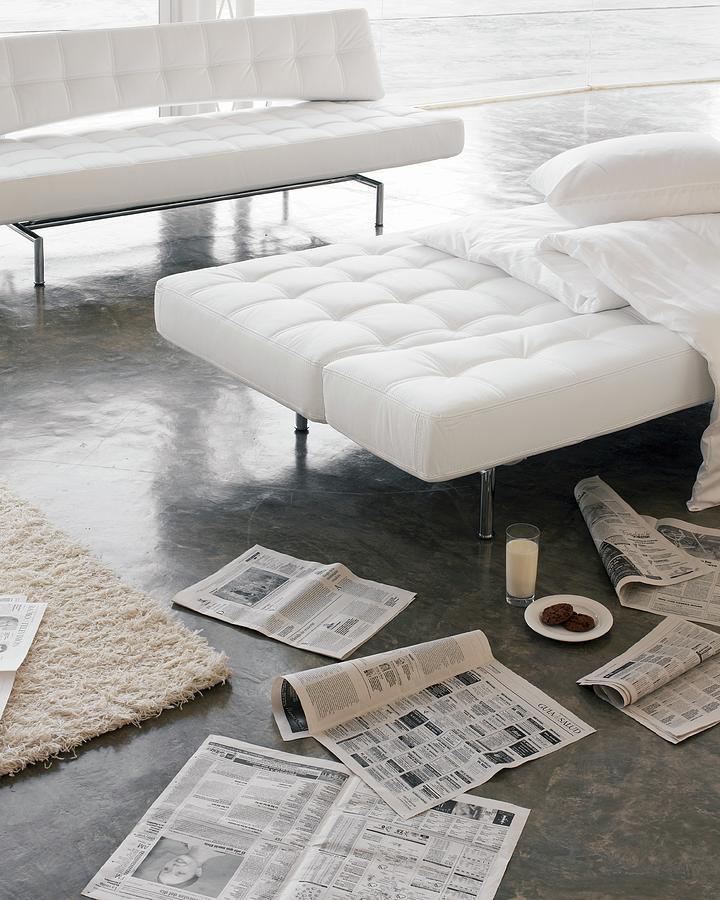 White Folding Sofas And Newspapers Scattered On Concrete Floor Photograph by Biglife