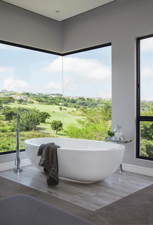 White Free-standing Bathtub In Front Of Frameless, Panoramic Corner Window With View Of Landscape Photograph by Great Stock!