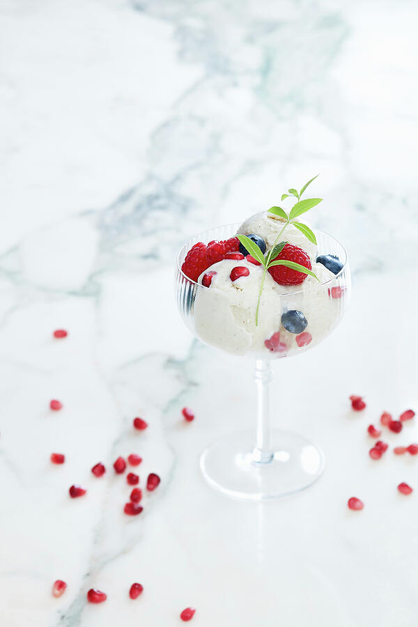Fruit Photograph - White Ice Cup With Raspberry Pomegranate Grains Blackcurrant Verbena Leaves On White Marble Background Inside by Frdric Jacquet