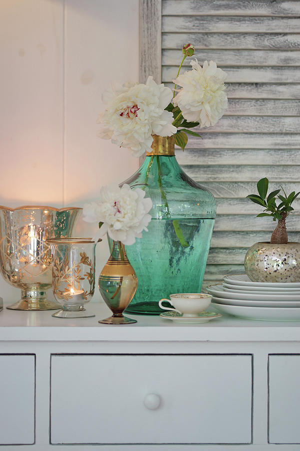 White Peonies In Turquoise Demijohn And Candle Lanterns On Chest Of Drawers Photograph by Angelica Linnhoff