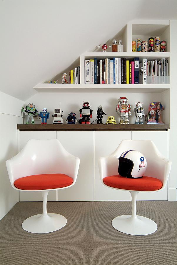 White Plastic Shell Chairs With Red Cushions In Front Of Sideboard And Shelving On Wall Of Attic Room Photograph by Wayne Vincent