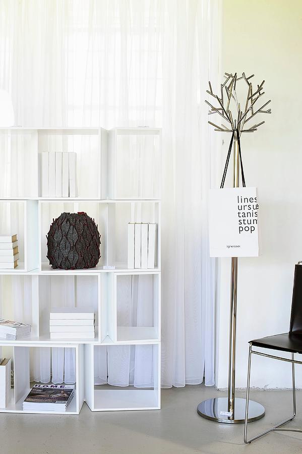 White Shelving Unit In Front Of Window Next To Metal Coat Rack Photograph by Beatrix Gallai