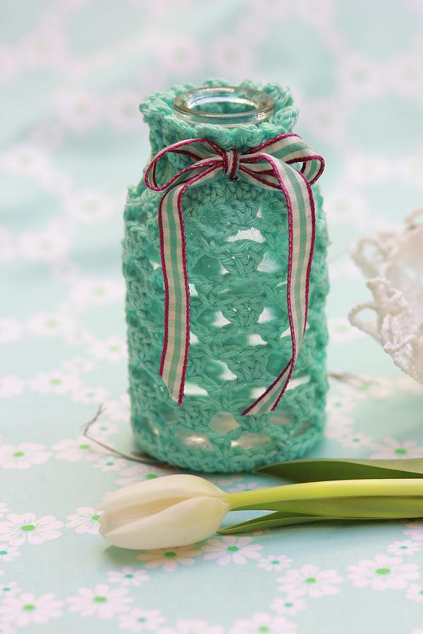White Tulip In Front Of Bottle With Hand-crocheted Cover And Ribbon Photograph by Ruth Laing