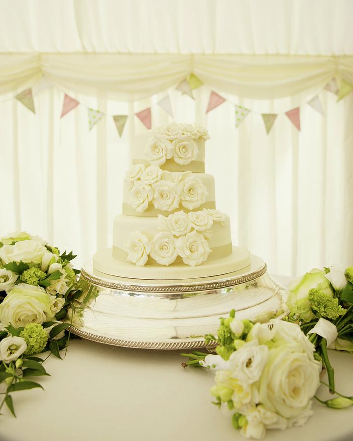 White Wedding Cake Surrounded By Bouquets Photograph by Jonathan Syer