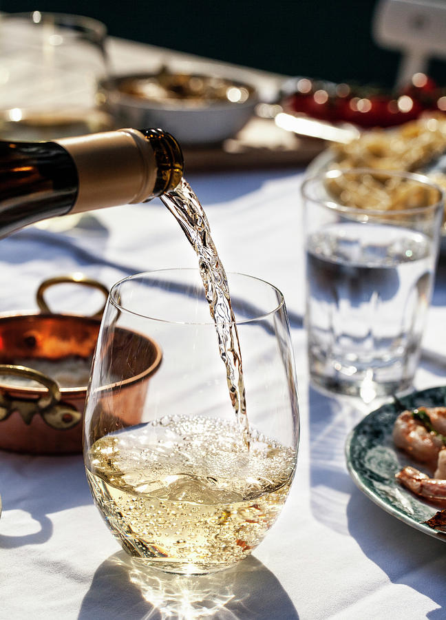 White Wine Being Poured Into A Glass, On An Outdoor Table With Pasta Cacio E Pepe cheese And Pepper, Basil And Shrimp Skewers Photograph by Ryla Campbell