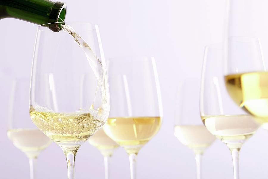 White Wine Pouring From Bottle Into Glass; White Background Photograph by Jalag / Gtz Wrage