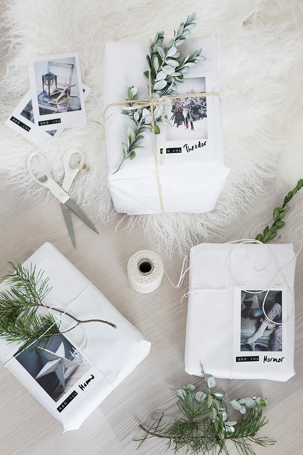 White-wrapped Christmas Gifts Decorated With Evergreen Sprigs And Photos Photograph by Annette Nordstrom