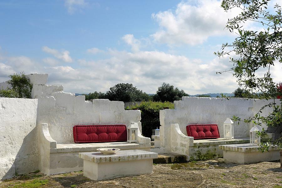 Whitewashed Masonry Benches And Tables With Red Seating Cushions In Front Of Open Landscape Photograph by Henri Del Olmo
