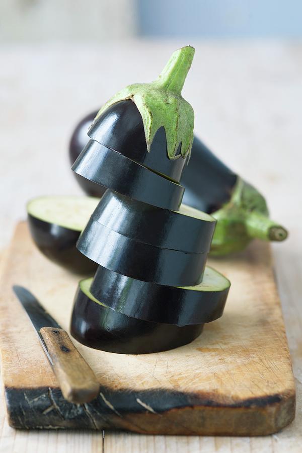 Whole And Sliced Eggplant On Wooden Chopping Board Photograph by Alena Hrbkov