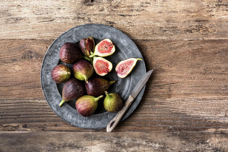 Whole And Sliced Figs On A Grey Plate On A Wooden Background Photograph by Sarah Coghill