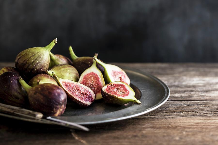 Whole And Sliced Figs On A Metal Plate With Knife On A Wooden Table Photograph by Sarah Coghill