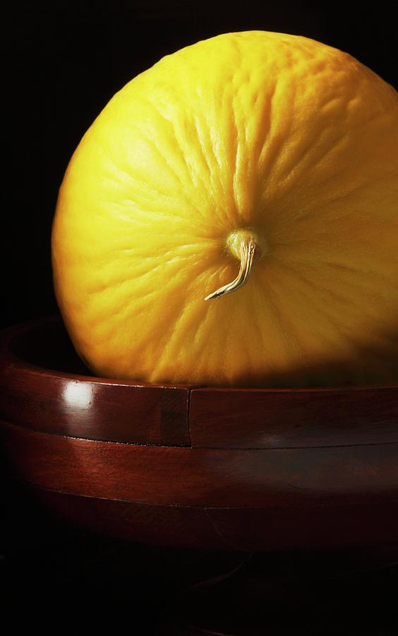 Whole Canary Melon On Dark Wood Pedestal Photograph by Katharine Pollak