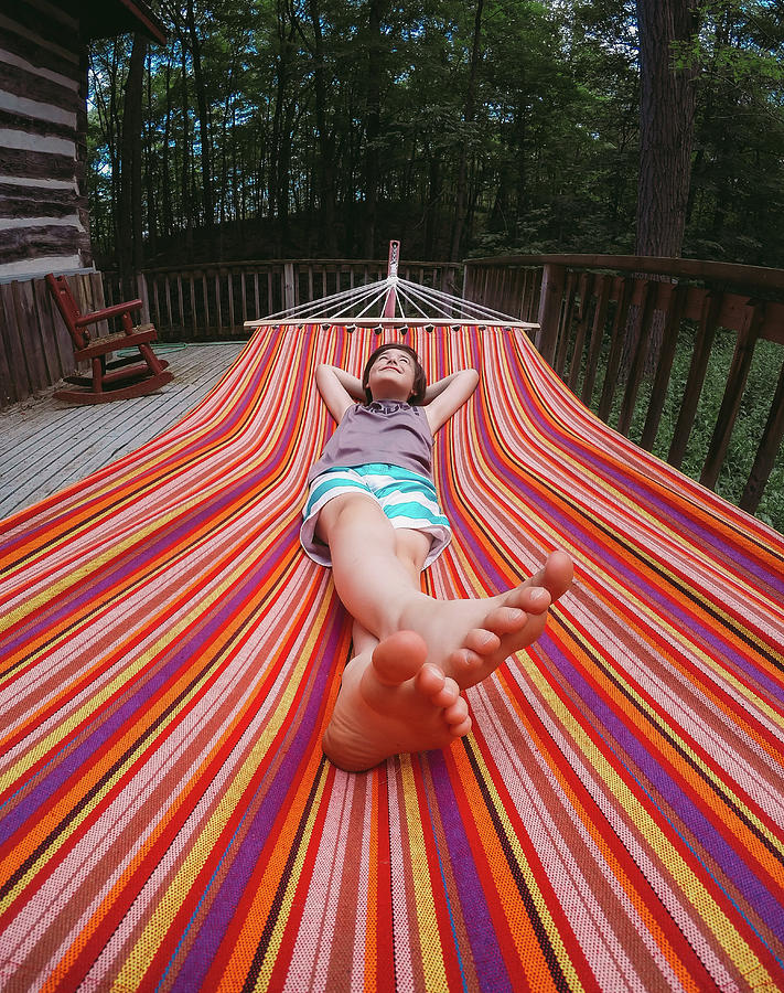 Tree Photograph - Wide Angle Of Young Boy Relaxing In A Striped Hammock On Cottage Deck. by Cavan Images
