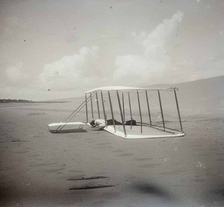 Wilbur Wright in prone position on glider just after landing, its skid marks visible behind it Painting by Celestial Images