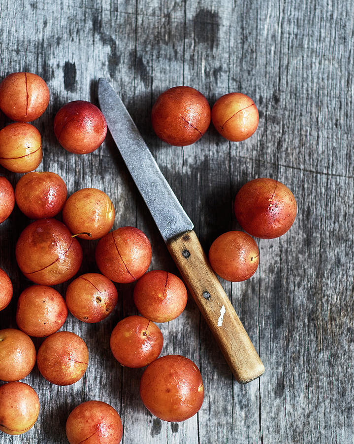 Wild Plums ringlovs With A Knife On A Wooden Surface Photograph by Miha Lorencak