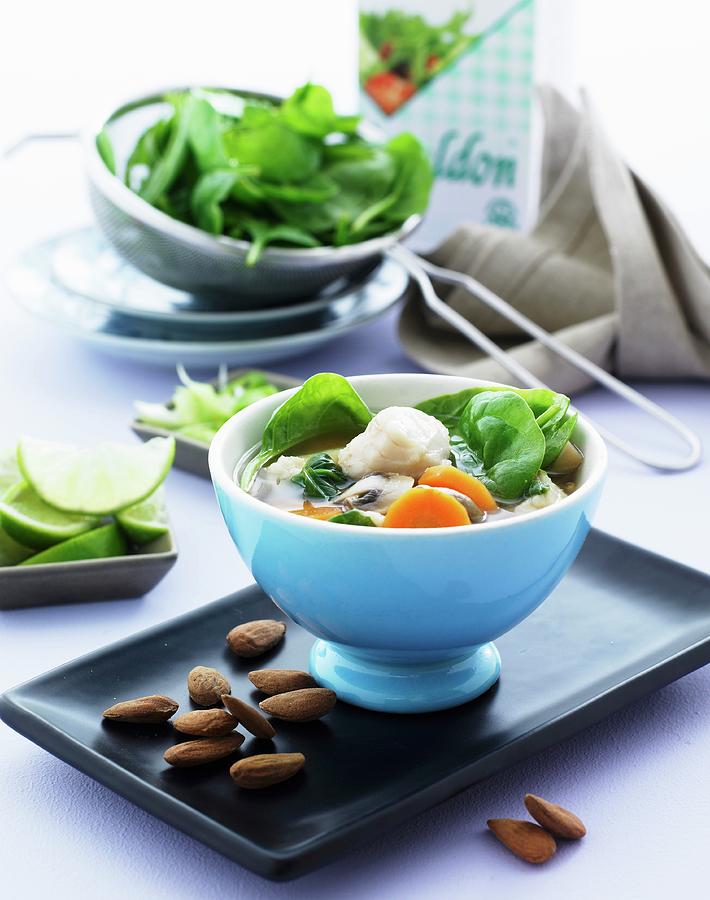 Winter Soup With Cod, Baby Spinach, Carrots, Limes And Almonds Photograph by Mikkel Adsbl