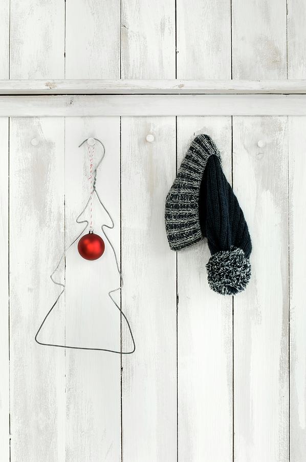 Wire Coat Hanger Bent Into Christmas Tree Shape And Bobble Hat Hung On White-painted Board Wall Photograph by Achim Sass