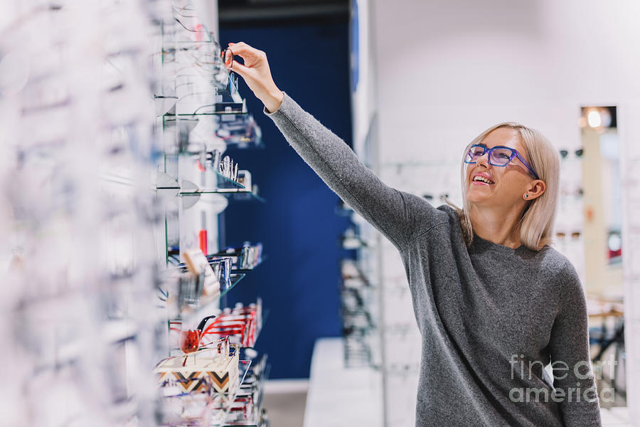 Woman choosing glasses at optic store. Photograph by Michal Bednarek