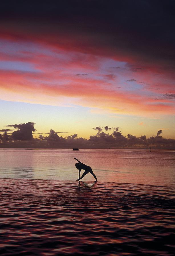 Woman Doing Yoga By Ocean At Sunset Photograph by Barry Winiker