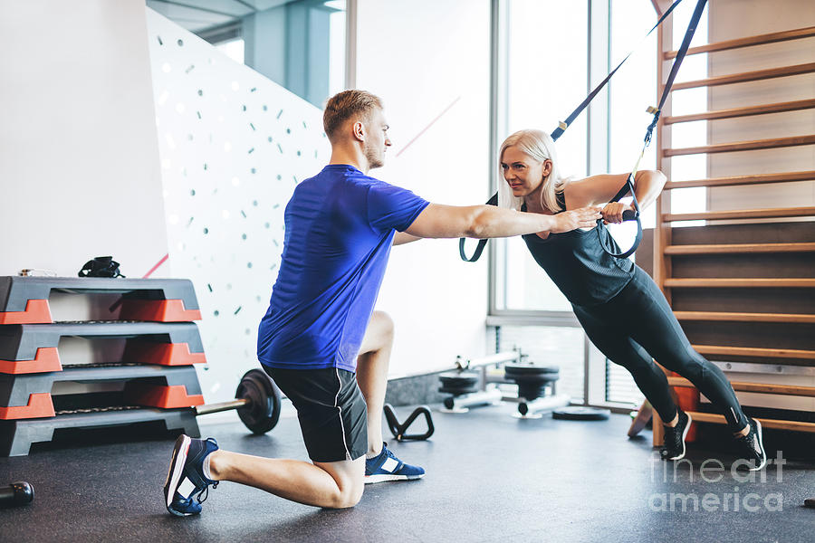 Woman exercising with personal trainer at the gym. Photograph by Michal Bednarek