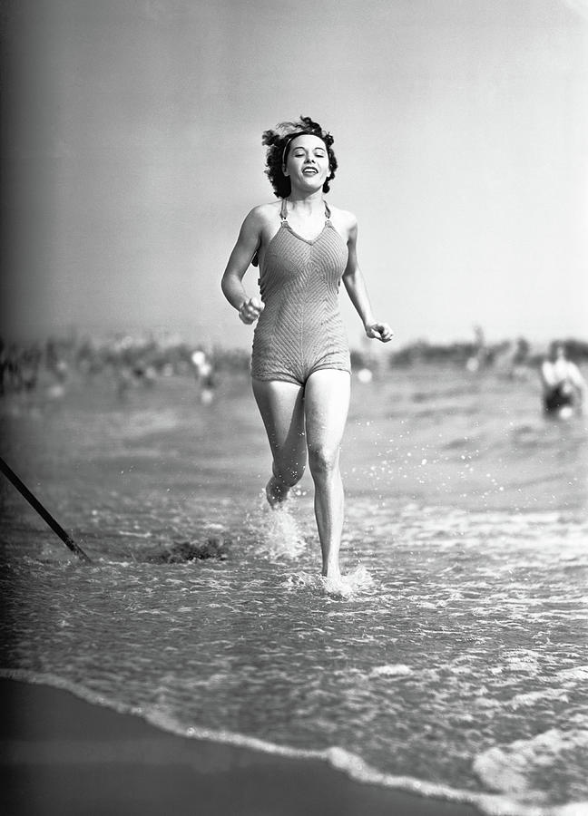 Woman In Swimsuit Running On Shoreline Photograph by George Marks