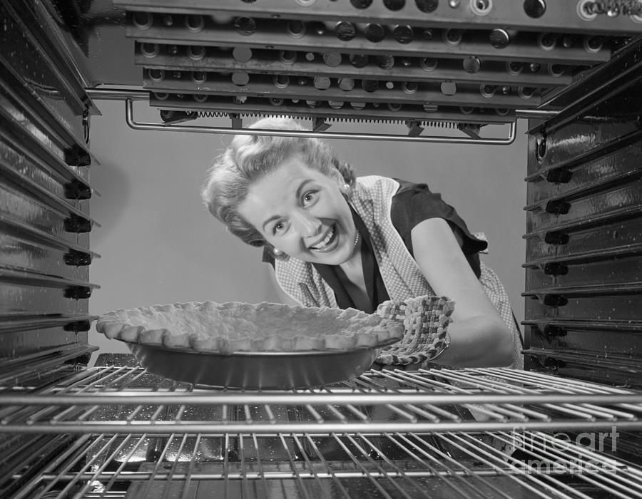Woman Looking At Pie In Oven Photograph by Bettmann