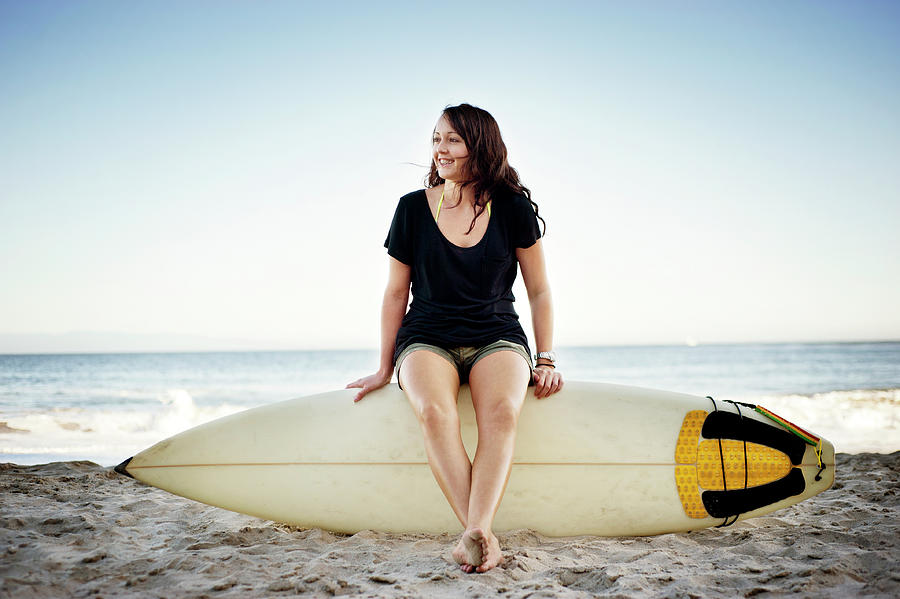 Nature Photograph - Woman Looking Away While Sitting On Surfboard At Beach by Cavan Images