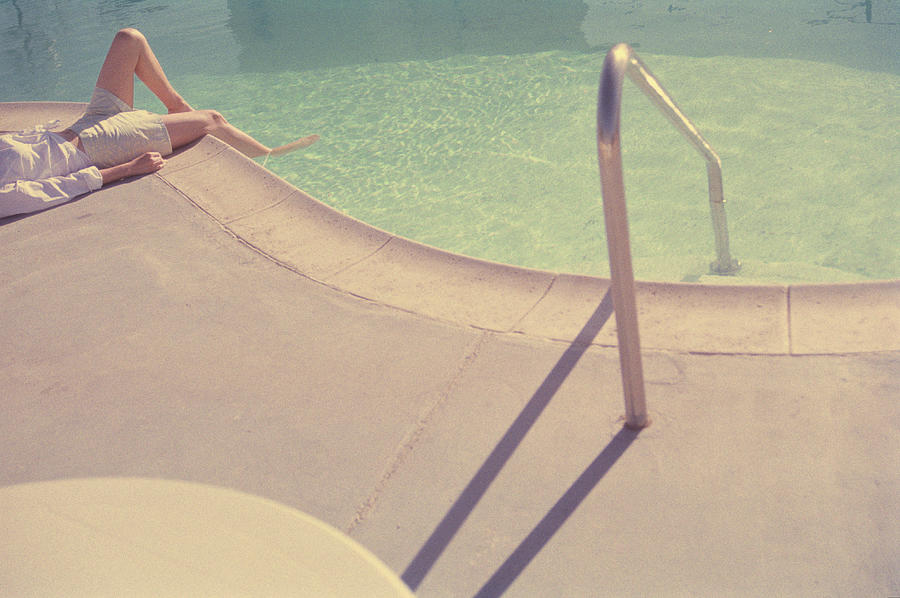 Woman Lying Next To Swimming Pool Photograph by Paul Taylor
