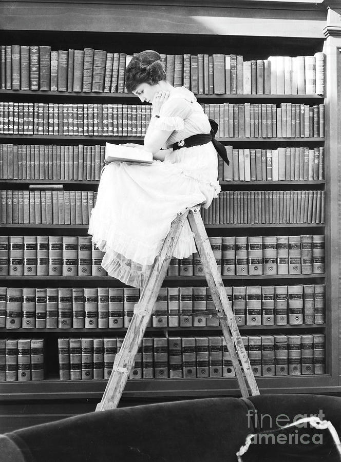 Woman Reading On Top Of Ladder Photograph by Bettmann