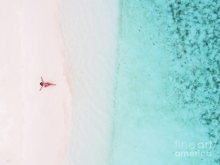 Woman relaxing on beach, aerial view, Maldives Photograph by Matteo Colombo