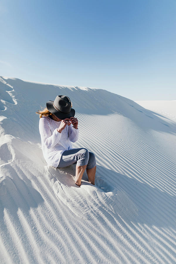 White Sands National Monument Photograph - Woman Wearing Hat Sitting On Desert At White Sands National Monument During Sunny Day by Cavan Images