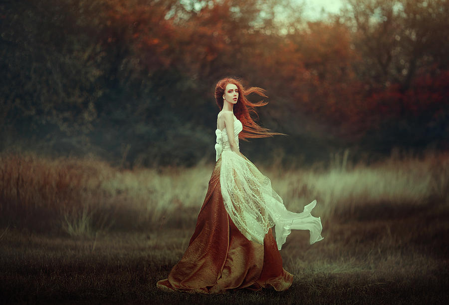 Woman With Long Red Hair In A Golden Medieval Dress Walking Through The Autumn Forest In The