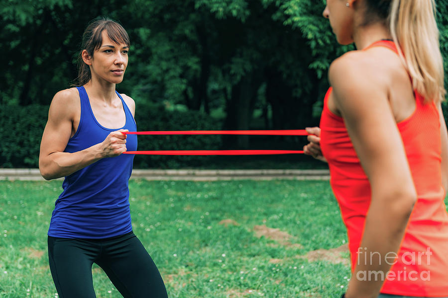Women Exercising With Elastic Bands In A Park Photograph by Microgen Images/science Photo Library