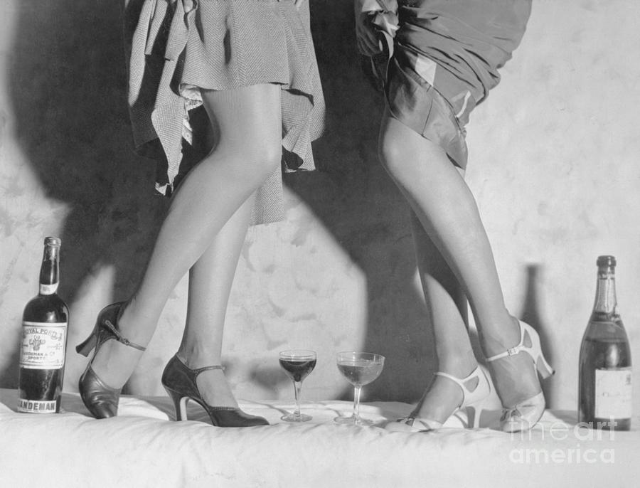 Women Modeling Shoes Near Wine Bottles Photograph by Bettmann