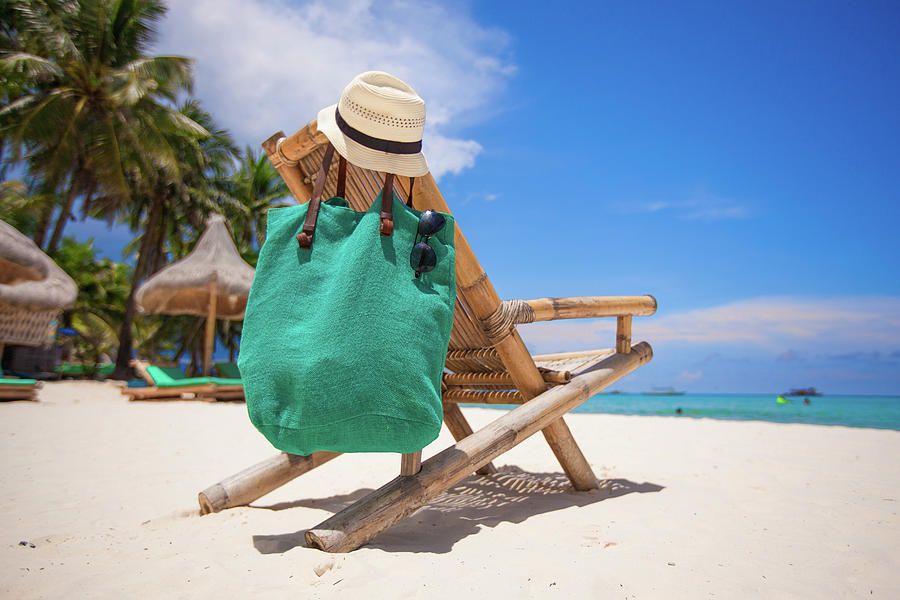 Wooden beach chair with hat and bag on white sand beach Photograph by ...