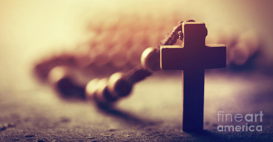 Wooden cross and rosary on stone background. Photograph by Michal Bednarek