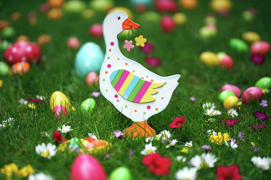 Wooden Goose On Lawn Amongst Flowers And Colourful Easter Eggs Photograph by Angelica Linnhoff