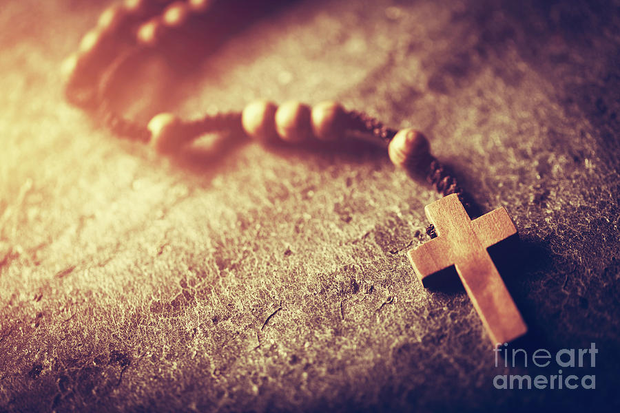 Wooden rosary with cross on stone background. Photograph by Michal Bednarek