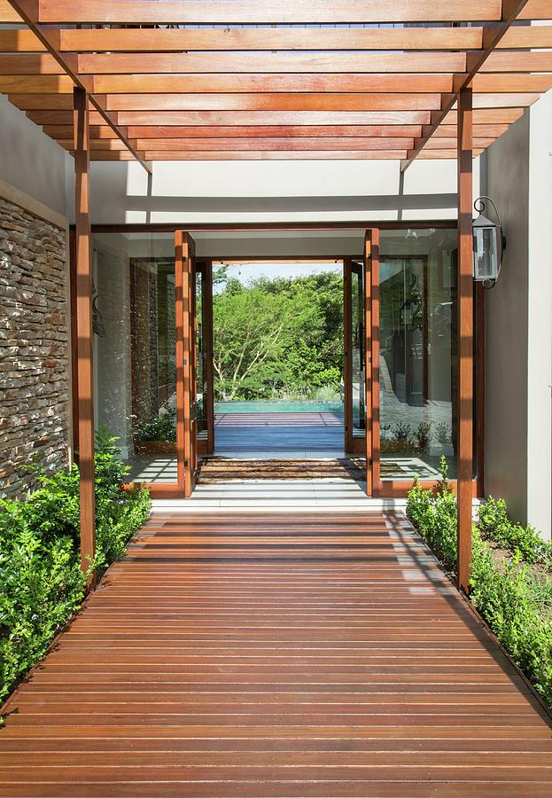 Wooden Walkway Below Wooden Pergola Leading To Entrance Of Modern House With View Through To Pool And Trees Photograph by Great Stock!