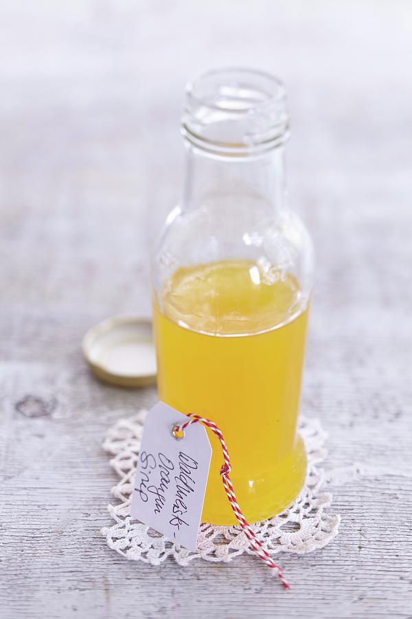 Woodruff And Orange Cordial In A Small Glass Bottle With A Cardboard Tag Photograph by Anke Schtz