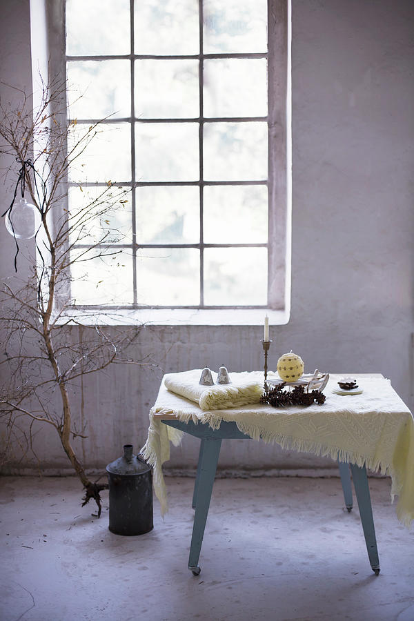 Woollen Blankets And Wintry Accessories On Table In Front Of Industrial-style Window Photograph by Alicja Koll