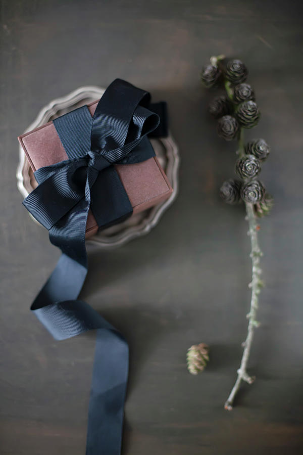 Wrapped Gift Decorated With Black Ribbon On Pewter Plate Photograph by Alicja Koll