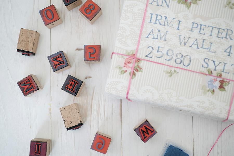 Wrapped Gifts With Old-fashioned, Hand-crafted Address Labels And Black Alphabet And Number Stamps On White, Vintage Wooden Surface Photograph by Studio27neun