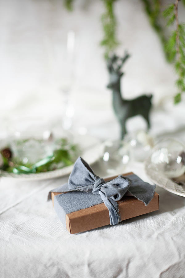 Wrapped Present On Table Set For Christmas Meal Photograph by Alicja Koll