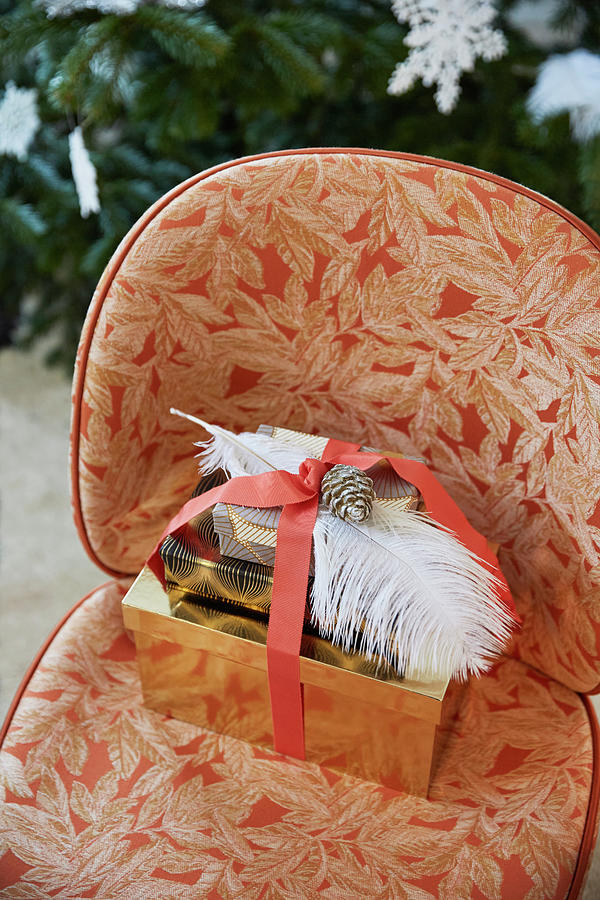 Wrapped Presents Decorated With Ribbon, Feathers And Pine Cones On Easy Chair Photograph by Birgitta Wolfgang Bjornvad