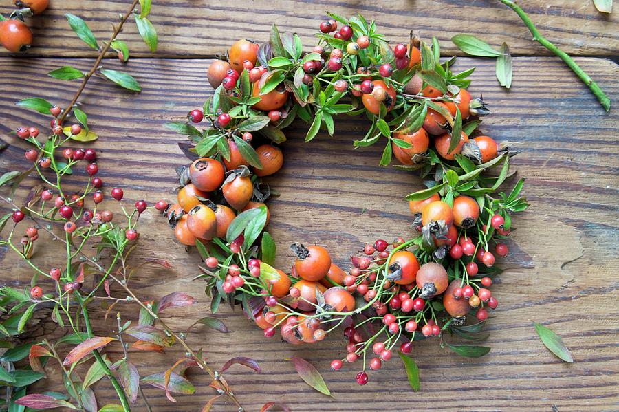 Wreath Of Rosehips On Wooden Table Photograph by Martina Schindler