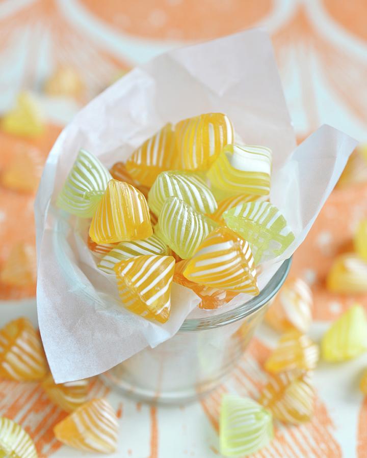 Yellow And White Striped Bonbons In A Glass Photograph by The Studio Collection