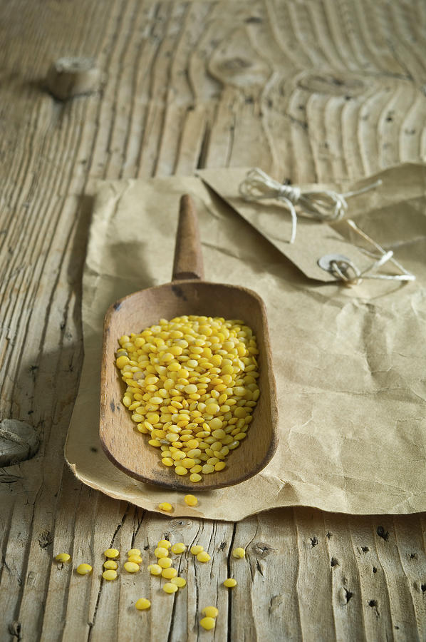 Yellow Lentils On A Wooden Scoop Photograph by Achim Sass