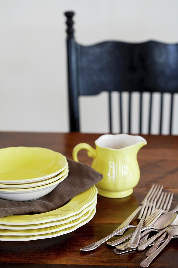 Yellow Plates, Bowls, Milk Jug And Cutlery On A Wooden Table Photograph by Jennifer Martine