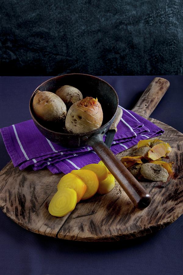 Yellow Turnips, Cooked, One Peeled And Sliced, On A Wooden Board And In An Old Metal Pan, With A Cloth And A Knife Photograph by Sabine Lscher